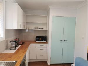 a kitchen with white cabinets and a microwave at Creekside Cottage - Private Studio with Mountain View in Coffs Harbour
