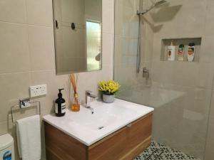 a bathroom with a white sink and a mirror at Creekside Cottage - Private Studio with Mountain View in Coffs Harbour +15 photos