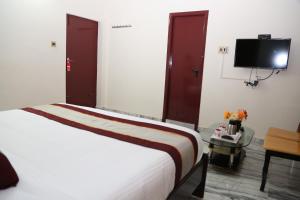 a hotel room with a bed and a flat screen tv at Sudha Grand Guestinn in Nellore