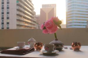 une table avec des tasses et un vase avec une fleur dans l'établissement Moderne Apartement La Defense Paris, à Courbevoie