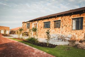 a stone house with tables and chairs in front of it at Die Kliphuis in Klerksdorp +15 photos