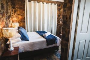 a bedroom with a bed with blue pillows and a window at Die Kliphuis in Klerksdorp