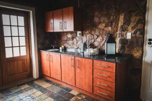 a kitchen with wooden cabinets and a stone wall at Die Kliphuis in Klerksdorp