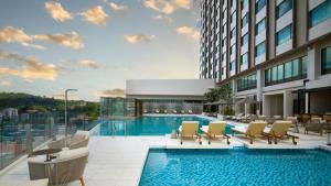 a swimming pool with chairs and a building at Ormond Sandakan in Sandakan