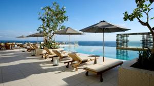 a row of lounge chairs and umbrellas next to a pool at Ormond Sandakan in Sandakan