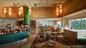 a restaurant with tables and chairs and a green pillar at Ormond Sandakan in Sandakan