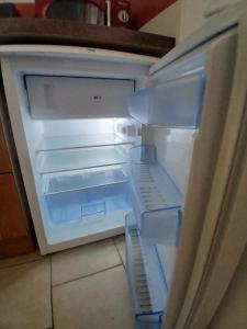 an empty refrigerator with its door open in a kitchen at Chez Lulu Grand Studio Cote Jardin avec Veranda in Saint-Sernin