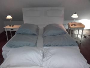 a white bed with two pillows on top of it at De Oude Smederij in Noord-Sleen