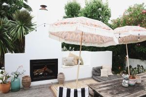 a patio with two umbrellas and a fireplace at Mr Banks in Robe
