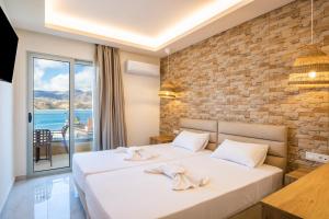 a bedroom with two beds and a brick wall at Dolphin Hotel Apartments in Karpathos