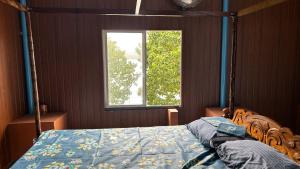 a bedroom with a bed with a blue comforter and a window at Athulya Tropical Paradise in Paravūr
