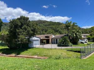 a house with a fence in a yard at Creekside Cottage - Private Studio with Mountain View in Coffs Harbour