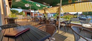 an outdoor patio with tables and chairs and green umbrellas at "Nesthocker" Café-Snackbar-Pension-Bauwagencamp in Offingen