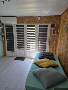 a bedroom with a green bed and some shuttered windows at Studette avec terrasse privée in Saint-Raphaël