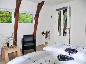 1 Schlafzimmer mit 2 Betten und einem schwarzen Stuhl in der Unterkunft Markermeerlogies in Bovenkarspel