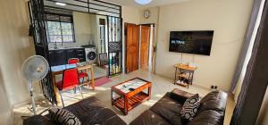 a living room with a couch and a flat screen tv at Mambo Number Five in Entebbe