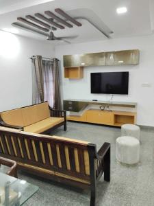 a living room with a couch and a flat screen tv at Relaxing Villa in Mysuru! in Mysore +1 photo