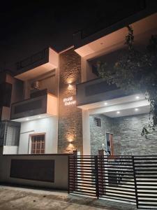 a building lit up at night with a fence in front at Relaxing Villa in Mysuru! in Mysore