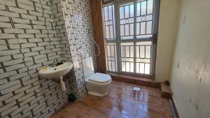 a bathroom with a sink and a toilet and a window at Mambo Number Five in Entebbe +28 photos