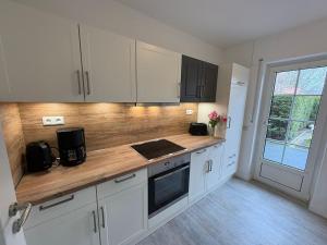 a kitchen with white cabinets and a wooden counter top at Achterdeck Kajüte in Dornumersiel +7 photos