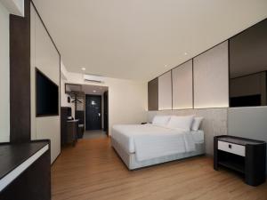 a bedroom with a white bed and a flat screen tv at Aston Kuta Hotel and Residence in Kuta