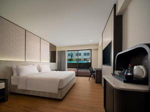 a hotel room with a bed and a television at Aston Kuta Hotel and Residence in Kuta
