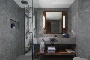 a bathroom with a sink and a shower with a mirror at Aston Kuta Hotel and Residence in Kuta
