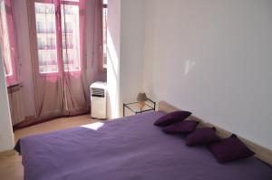 a bedroom with a bed with purple sheets and pillows at Spacieux & Lumineux appartement - Centre de Cannes in Cannes