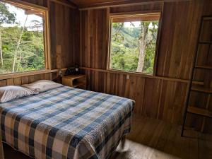 a bedroom with a bed and two windows at Rancho Ecojoya Paradise Mountain working farm in nature in San Isidro de El General