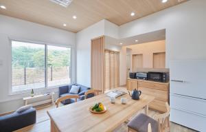 a kitchen and living room with a wooden table and chairs at 森のRetreat -foresta di luce- in Hatsukaichi