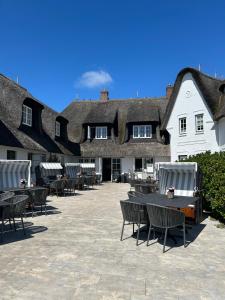 a patio with tables and chairs in front of a building at Strandvogtei Sylt - Boutique Hotel & Houses in Rantum