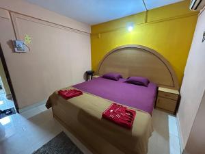 a bedroom with a bed with purple sheets and purple pillows at Dmello guesthouse in Palolem