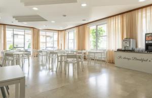 a dining room with tables and chairs and windows at Hotel Levante Convenzionato con ACQUARIO DI CATTOLICA in Riccione