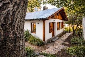 a small house with a metal roof next to a tree at Centrally located lakefront house in San Carlos de Bariloche