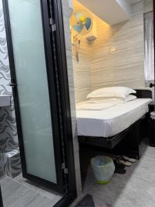 a small bed in a room with a glass door at Mabuhay INN in Hong Kong