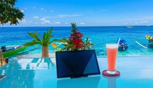 a television and a drink on a table with the ocean at Bunaken Paradise Beach Homestay in Bunaken