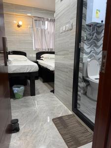 a small room with a bathroom with two beds at Mabuhay INN in Hong Kong
