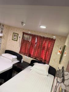 two beds in a room with a red window at Mabuhay INN in Hong Kong