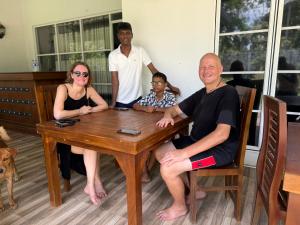a group of people sitting around a wooden table at Singha Holiday Bungalow in Ibbagomuwa