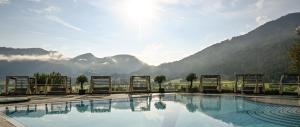 a large swimming pool with mountains in the background at IMLAUER Hotel Schloss Pichlarn in Aigen im Ennstal