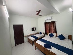a bedroom with two beds and a ceiling fan at Teja Residency in Alāndurai