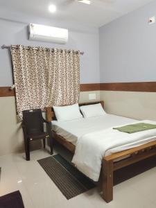 a bedroom with a bed and a chair at SJ Residency in Dharmastala +9 photos
