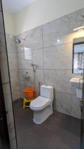 a bathroom with a white toilet and a sink at SJ Residency in Dharmastala