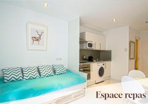 a bedroom with a blue bed and a kitchen at Apt 4 Eaux-Chaudes proche Laruns et Espagne in Laruns