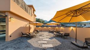 a patio with tables and chairs and umbrellas at Wuye WOO YEAH Tangchi Hotel in Emeishan City