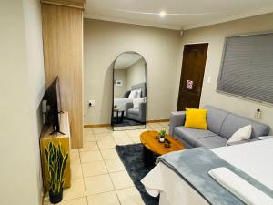 a room with a bed and a couch and a mirror at Hei Stays Bachelor Apartment in Bronkhorstspruit