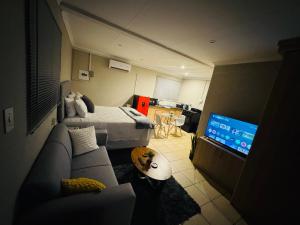 a room with a bed and a couch and a television at Hei Stays Bachelor Apartment in Bronkhorstspruit +8 photos
