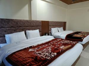 two beds sitting next to each other in a bedroom at Shree Kuber Regency in Badrinath