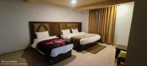 a hotel room with two beds and a window at Shree Kuber Regency in Badrinath +2 photos