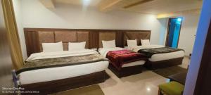 two beds in a hotel room withskirts at Shree Kuber Regency in Badrinath